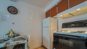 A kitchen with a refrigerator, stove, and wall clock. - Logis near university, parking & Wi-Fi (Rouyn-Noranda)