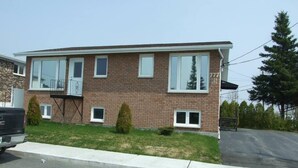 A two-story residential building with a brick facade, multiple windows, and a visible address number. - Logis near university, parking & Wi-Fi (Rouyn-Noranda)