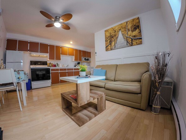 A compact living space with a kitchenette, a dining area, and a seating area with a sofa and a coffee table.