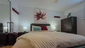 A hotel room with a large bed, a headboard, a wall-mounted artwork, a wardrobe, and a mirror. - Logis near university, parking & Wi-Fi (Rouyn-Noranda)