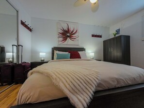 A hotel room with a large bed, a headboard, a wall-mounted artwork, a wardrobe, and a mirror. - Logis near university, parking & Wi-Fi (Rouyn-Noranda)