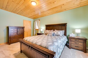Una camera da letto con un letto di legno, un comodino con una lampada, una cassettiera e una porta.