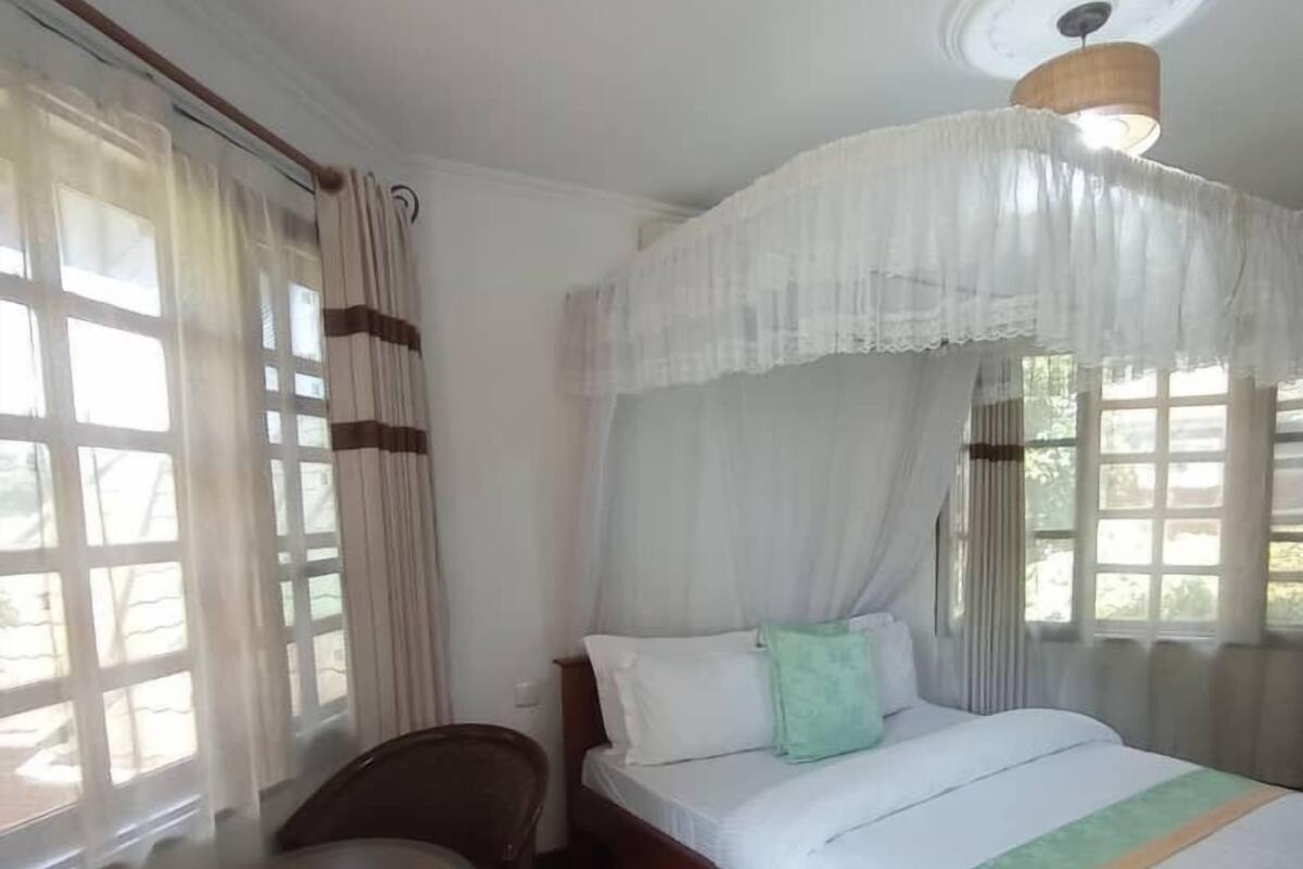 A room with a bed, a chair, a small table, and a window with curtains.