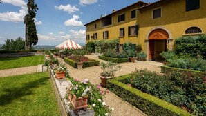 A courtyard with a yellow building, a red and white striped tent, and well-maintained gardens. - Villa in La Presura with 8 bedrooms sleeps 16 (La Presura)