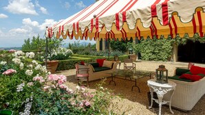 An outdoor seating area with a striped awning, wicker furniture, and a view of a garden with roses. - Villa in La Presura with 8 bedrooms sleeps 16 (La Presura)