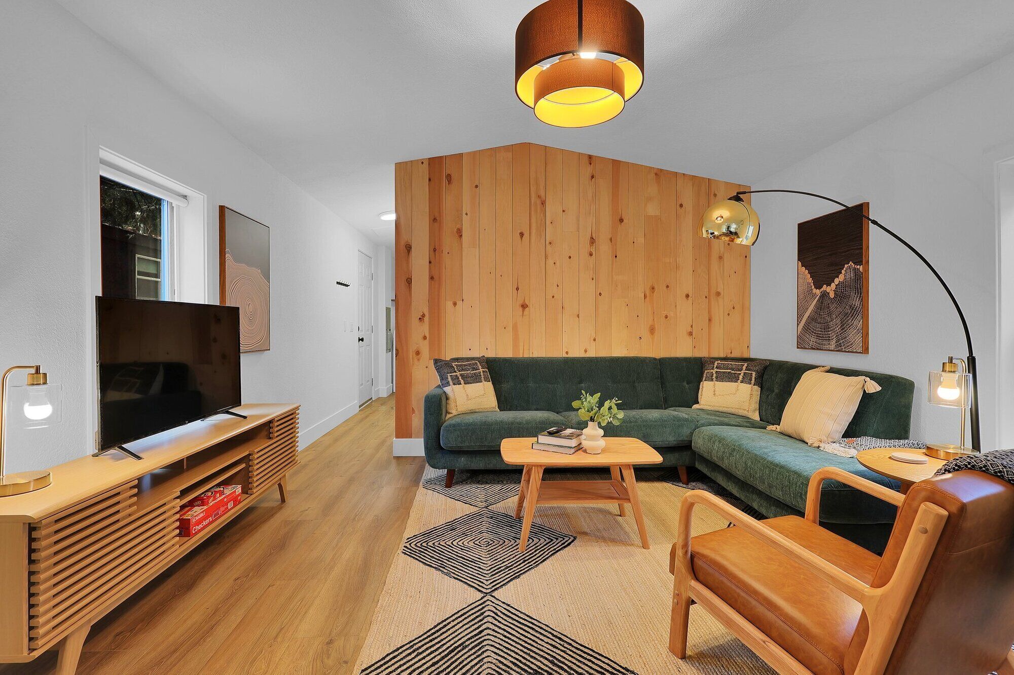 Uma sala de estar moderna com uma parede de destaque em madeira, um sofá verde, uma mesa de centro de madeira e uma TV em um suporte de madeira.