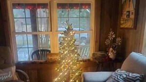A cozy living room with a Christmas tree, a couch, and a rug.