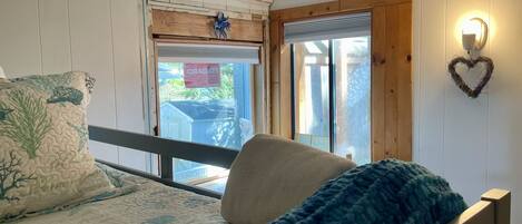A bedroom with a bed, a window, and a heart-shaped wall decoration.
