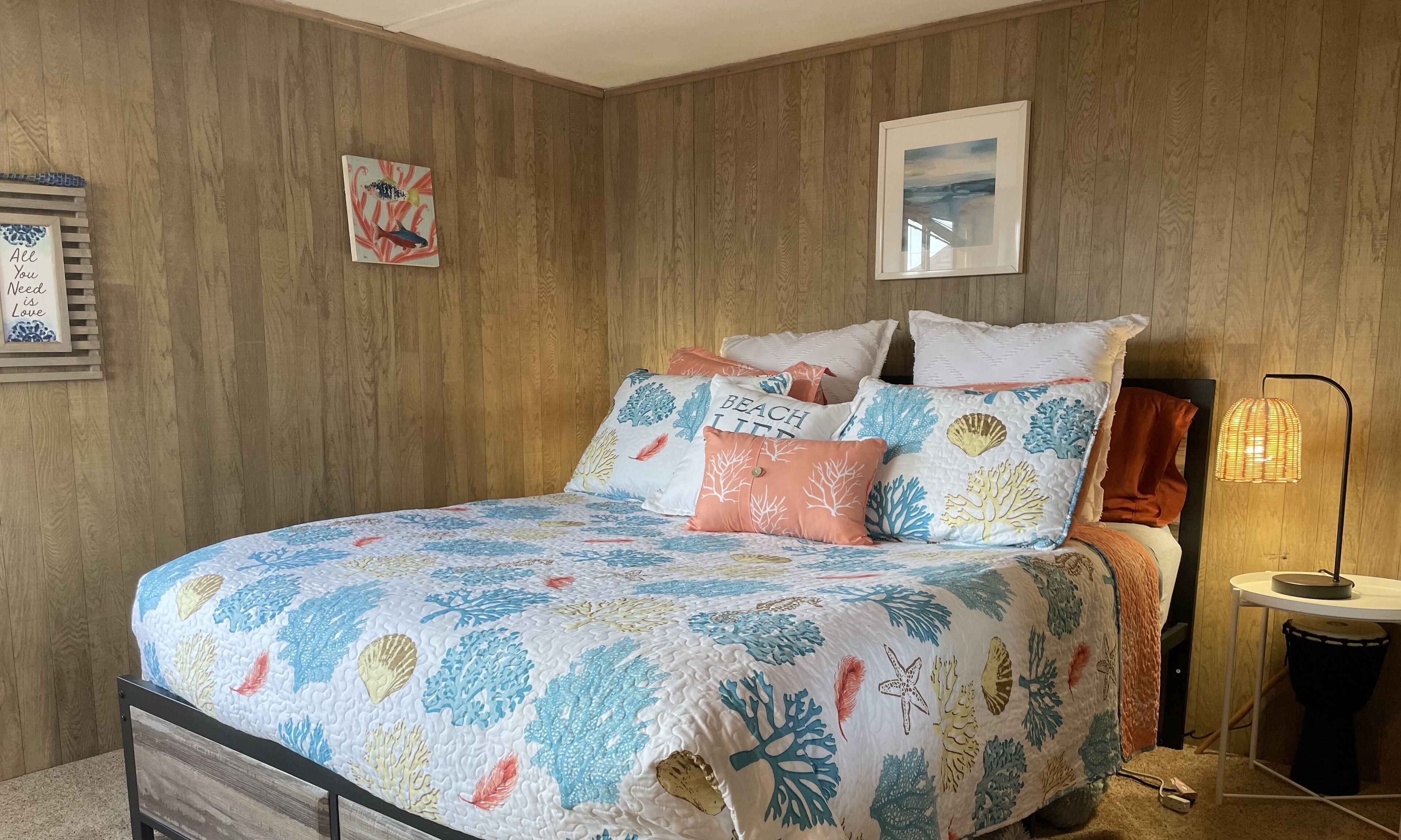 Een slaapkamer met een bed, houten wanden, een lijst met een afbeelding en een bedlamp.