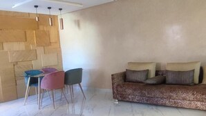 Un salon doté d’un sol en marbre, d’un canapé marron avec des coussins et de trois fauteuils.