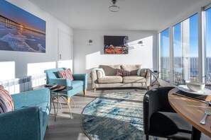 A modern living room with a large window, a round coffee table, and two sofas.