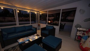 A covered outdoor seating area with a sofa, chairs, and a coffee table.