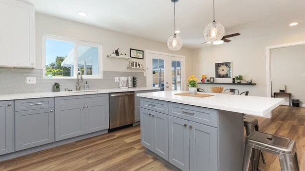 A modern kitchen with grey cabinets, a central island, and pendant lighting.