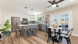 A modern kitchen with white cabinets, stainless steel appliances, and a central island with stools.