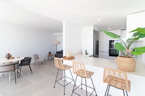 A modern kitchen with white cabinetry, a large island, and a potted plant.