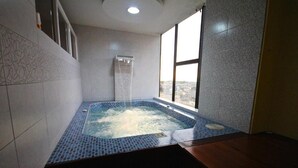 A hot tub with a view of the city through large windows. - HOTEL GOLDEN VISTA (Santo Domingo de los Colorados)
