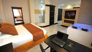 A hotel room with a bed, a laptop, a TV, and a bathtub. - HOTEL GOLDEN VISTA (Santo Domingo de los Colorados)