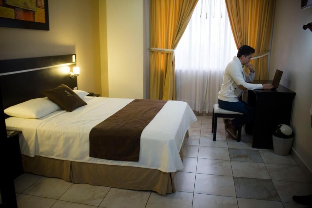 Una habitación de hotel con cama, escritorio y ordenador portátil.