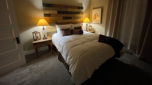 Et pænt indrettet hotelværelse med en stor seng, to sengeborde, en sengegavl med træpaneldesign og to lamper.