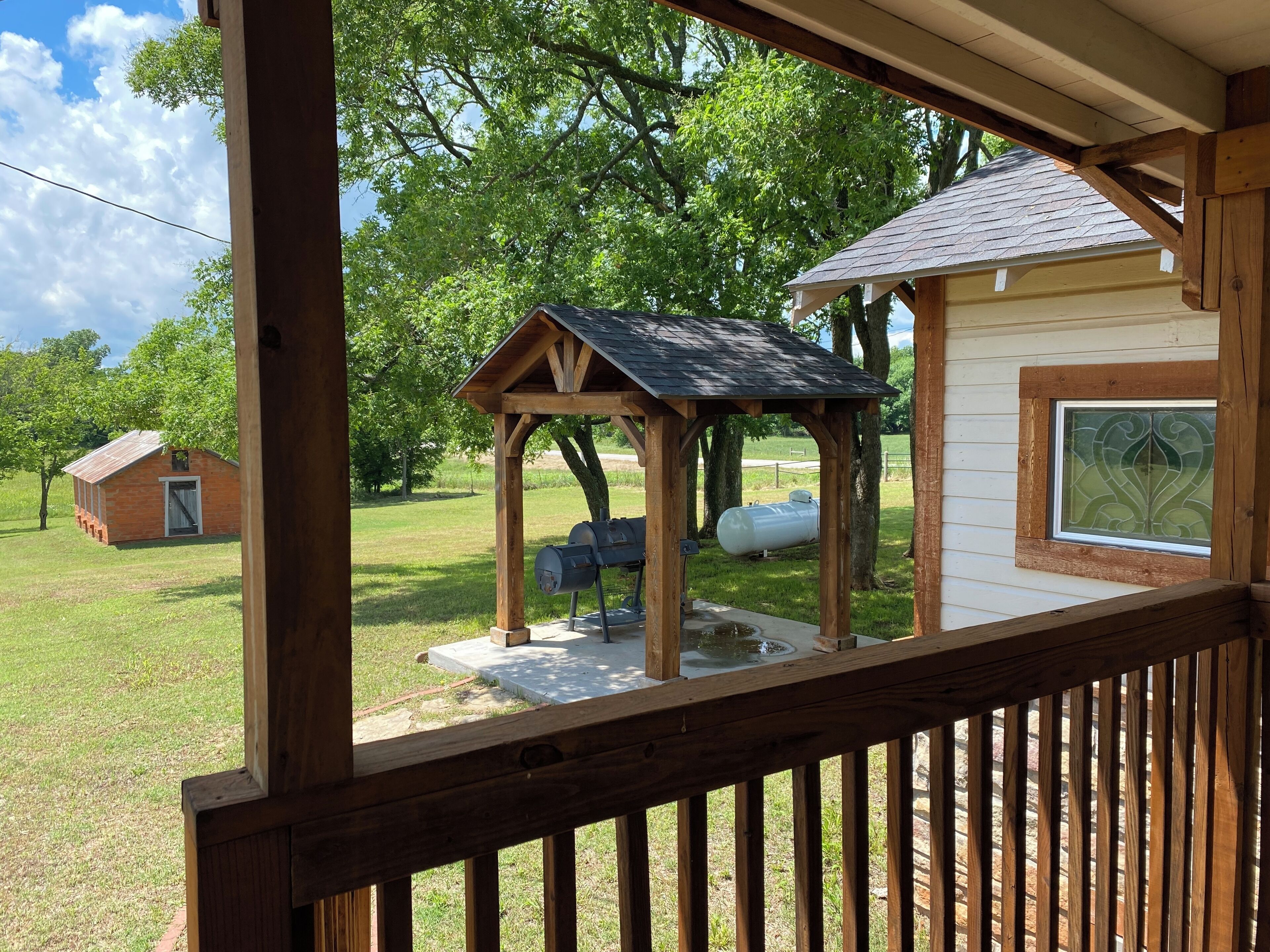 Une terrasse en bois avec un kiosque et un petit bâtiment en arrière-plan.