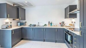 A modern kitchen with grey cabinets, a microwave, a toaster, and a sink. - Gospel Heights by Guestz (Heswall)