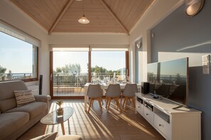 A modern living room with a sofa, coffee table, TV, and dining area with chairs and a table.