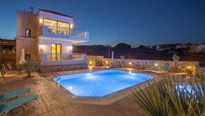 A two-story building with a swimming pool, outdoor seating, and a stone wall. - Kladissos Family Seaside Villa with heated pool, hydromassage and barbecue! (Agia Pelagia)