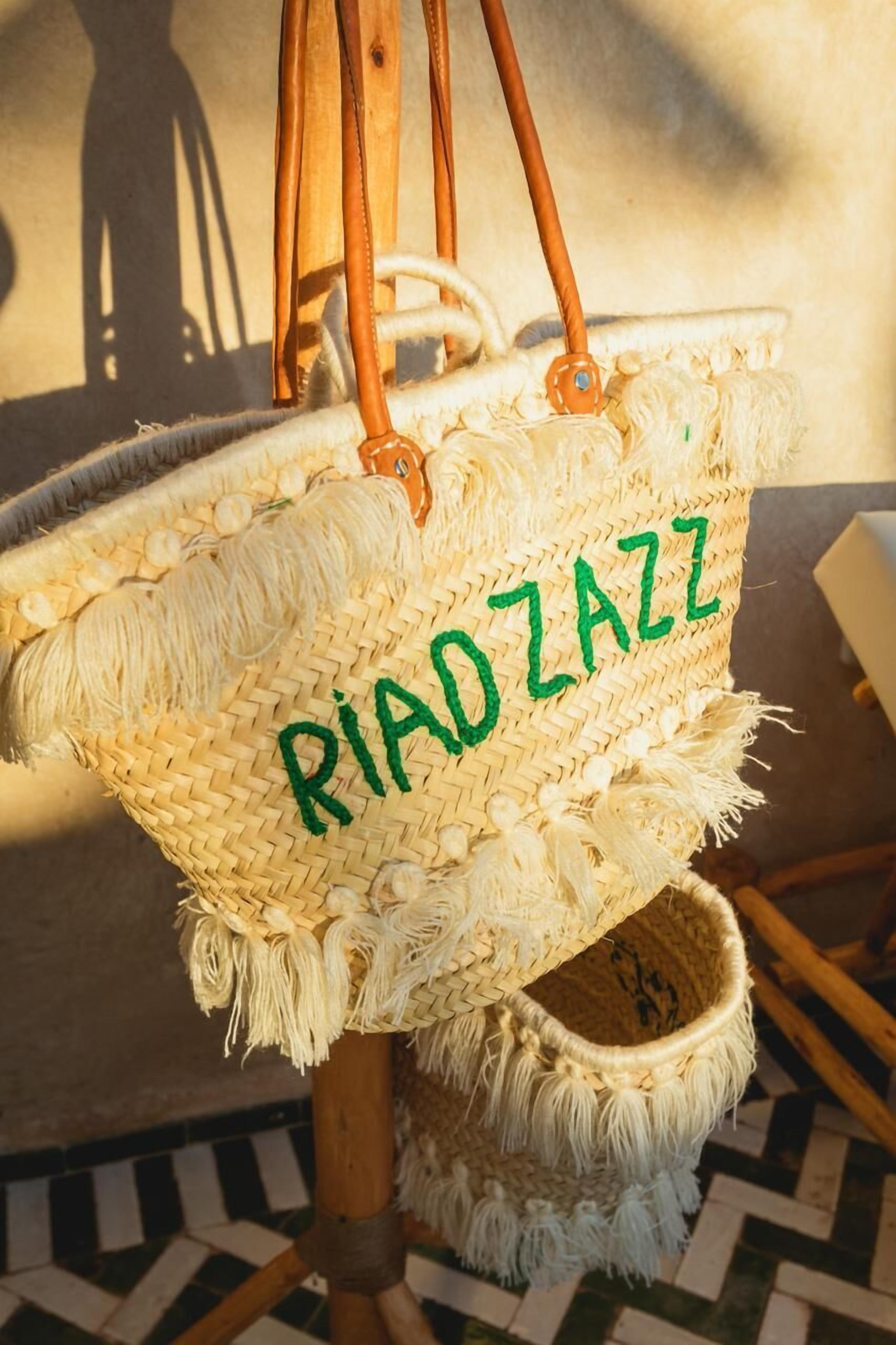 Punottu kori, jossa on teksti ”RIADZAZZ”, ja joka on ripustettu puiseen rakenteeseen.