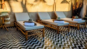 Un espace détente avec trois chaises longues, un sol à motifs et des œuvres d’art décoratives murales.