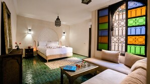 Une chambre à coucher comprenant un lit, un canapé, une table basse et une fenêtre ornée de vitraux colorés.