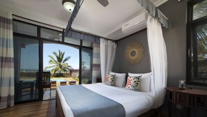 A bedroom with a large bed, a view of the pool and palm trees, and a ceiling fan.