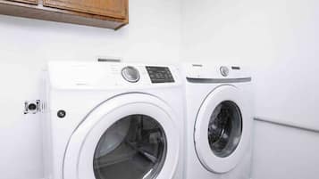 A laundry room with two white front-loading washing machines, wooden cabinets, and a wooden ceiling.