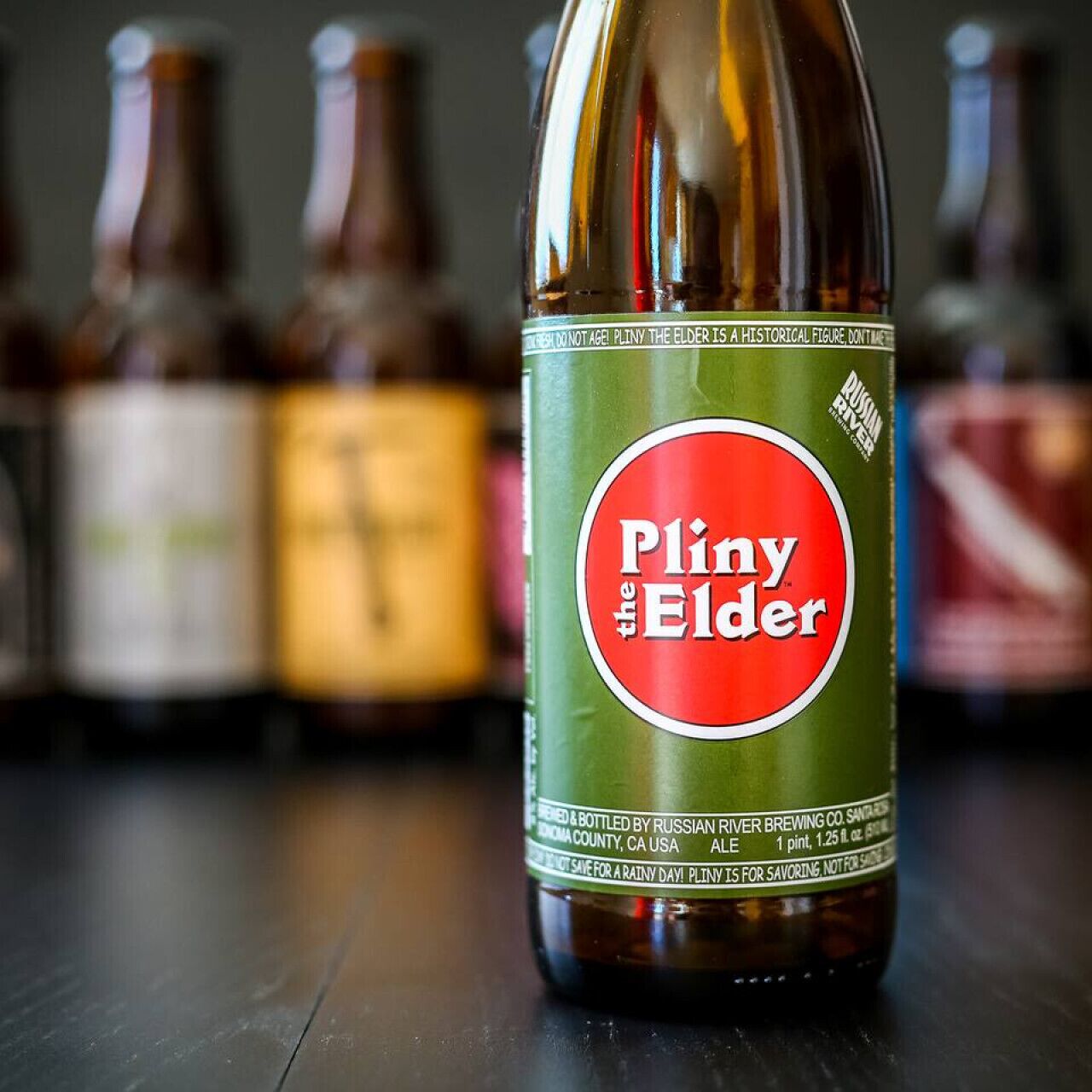 A bottle of Pliny the Elder beer with a green label and a red circle.