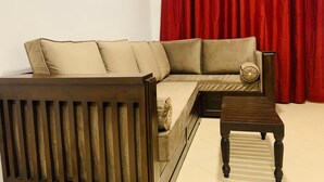 A living room with a sofa, a wooden coffee table, and a red curtain in the background.