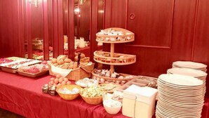 A buffet table with various food items and utensils, including bread, pastries, and bowls. - Sonnenstrand Hotel (Butjadingen)