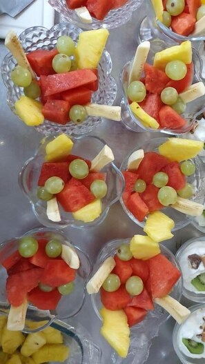 A tray of fruit cups with watermelon, grapes, and pineapple chunks. - Sonnenstrand Hotel (Butjadingen)