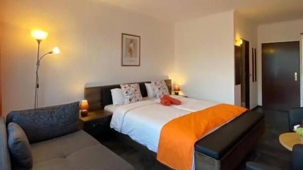 A hotel room with a bed, a sofa, a small table, and a nightstand. - Sonnenstrand Hotel (Butjadingen)