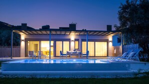 Ein modernes Haus mit Swimmingpool, Sitzgelegenheiten im Freien und einer überdachten Terrasse.