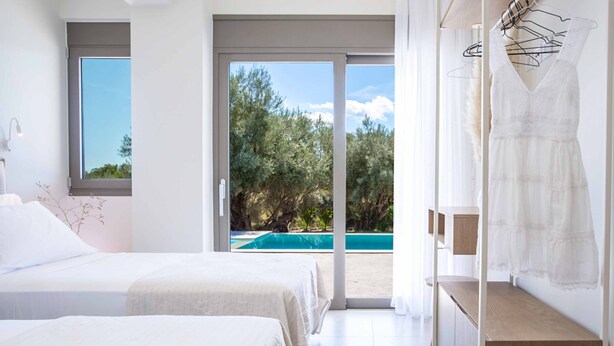 Ein Schlafzimmer mit zwei Betten, Blick auf einen Pool und ein Balkon mit Blick auf Bäume.