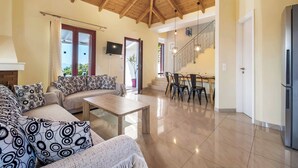 Amplia sala de estar con techo de madera, un conjunto de sofás, una mesa de centro y un comedor con sillas y una mesa.
