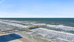 A pier extending into the ocean with a sandy beach area. - Beachview Luxury Condo Decks & Views (Daytona Beach)