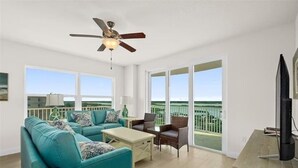 A spacious living room with a teal sofa, a coffee table, and a TV on a wooden stand. - Beachview Luxury Condo Decks & Views (Daytona Beach)
