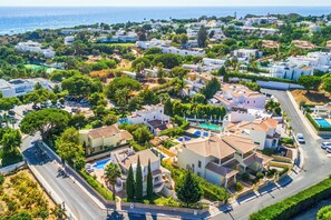 A coastal residential area with houses, a swimming pool, and a road. - Villa Katharina - Three Bedroom Villa, Sleeps 6 (Albufeira)