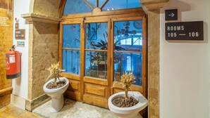 A hotel entrance with a wooden door, potted plants, a fire extinguisher, and a sign indicating rooms 105-106. - The Indy House | Room 106 by LovelyStay (Lisboa)