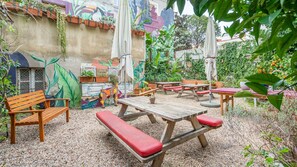 Relax in a charming outdoor space with benches, picnic tables, and lush greenery.