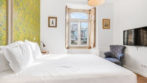 Een hotelkamer met een groot bed, een stoel, een televisie en een raam met uitzicht op de stad.