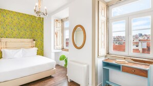 A bedroom with a bed, a dresser, a mirror, and a window with a city view.
