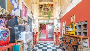 A hallway with a checkered floor, a staircase, and a mix of modern and vintage furniture.