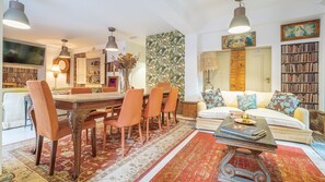 A spacious living room with a large dining table, comfortable seating, a bookshelf, and a cozy fireplace. - The Indy House | 502 by LovelyStay (Lisboa)