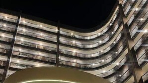 Un edificio moderno con una facciata curva e una struttura circolare centrale con finiture in legno.